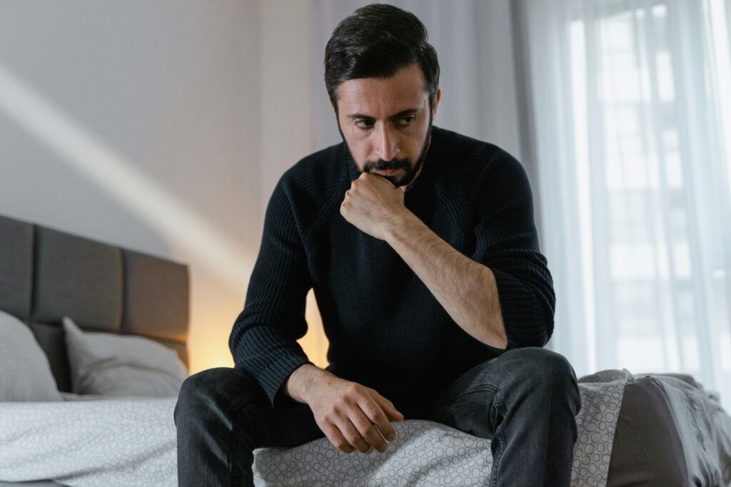 man sitting on bed thinking